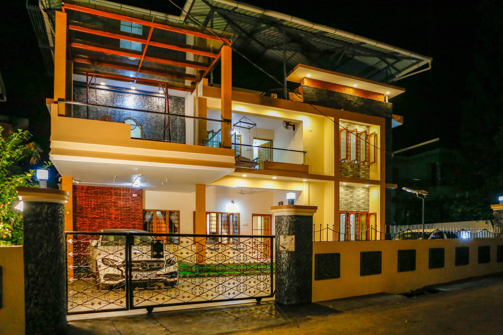 The villa lit after dark, seen from the street